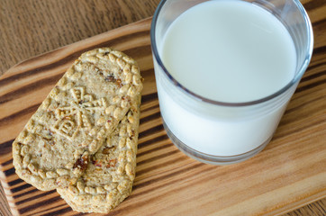 Glass of milk with wholegrain cookies on wooden desk. top view. close-up