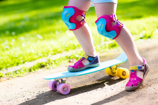 Child riding skateboard in summer park