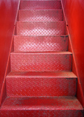 bright red painted metal staircase with steps made of steel plate with a textured surface and...