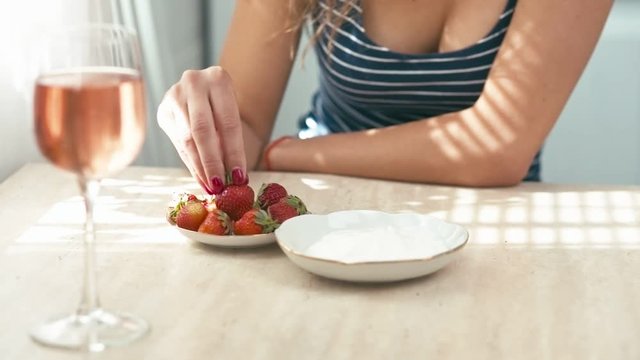 Beautiful young woman eats strawberry with cream, slow motion, tripod shot, shallow depth of field