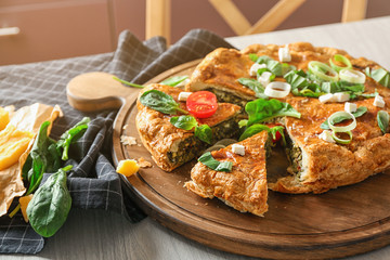 Tasty pie with spinach on wooden board