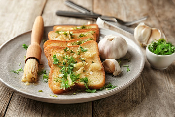 Plate with delicious homemade garlic bread on table