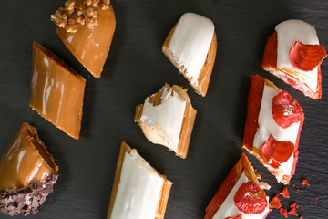 Tasty cut eclairs on black background, top view