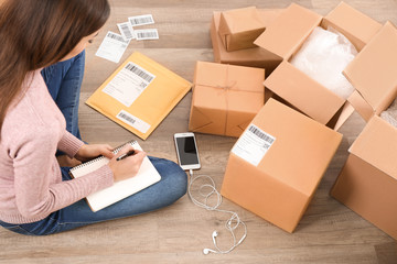 Woman preparing parcels for shipment to customer on floor