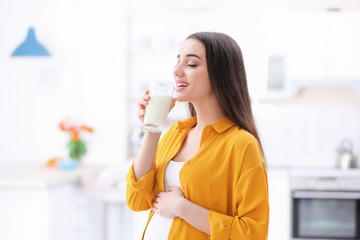 Beautiful pregnant woman drinking milk at home