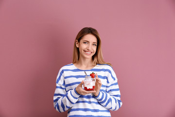 Young attractive woman eating tasty yogurt on color background