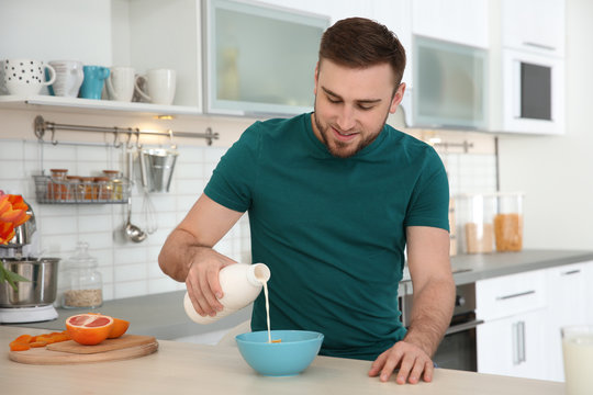 Young man having breakfast with tasty milk at home