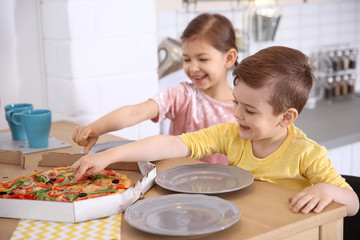 Cute little kids eating tasty pizza at home