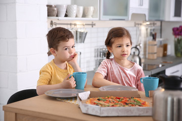 Obraz na płótnie Canvas Cute little kids eating tasty pizza at home