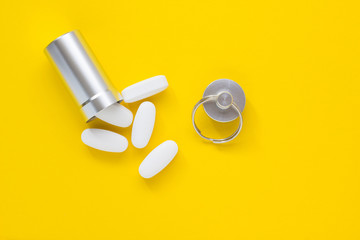 Metal container and pills on a yellow background, close-up