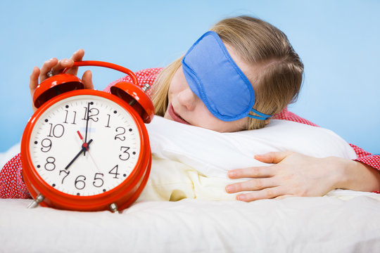 Sleeping woman wearing pajamas holding clock