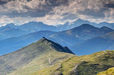 Mountain hut at top of Helm Elmo peak on Karnischer Hohenweg trail in Alpi Carniche Karnische Alpen with Rieserferner and Villgraten Mountains of High Tauern in background, Tyrol Italy Austria Europe
