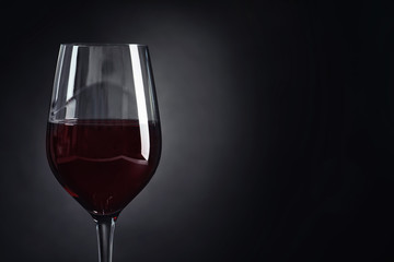 Glass with delicious red wine on dark background