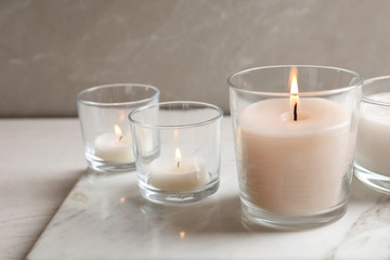 Burning candles in glasses on marble board