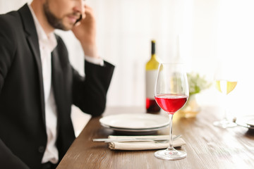 Man with glass of wine at table in restaurant