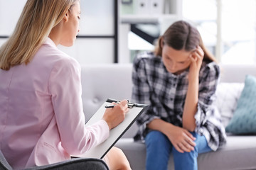 Child psychologist working with teenage girl in office - obrazy, fototapety, plakaty