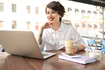 Young woman working with laptop at desk in cafe