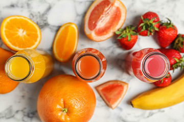 Flat lay composition with tasty juices and ingredients on marble background