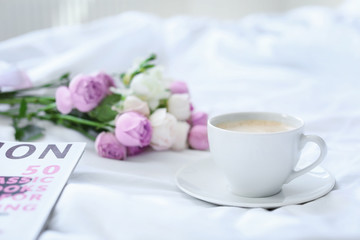 Fototapeta na wymiar Cup of coffee, beautiful flowers and magazine on fabric