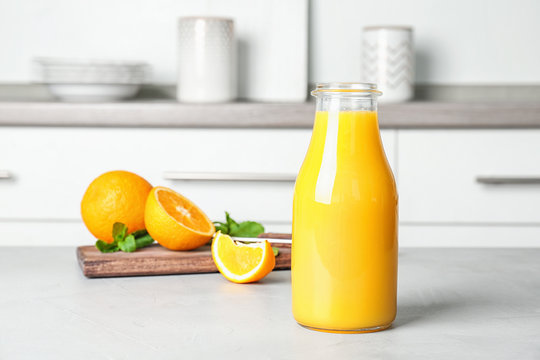 Bottle with fresh orange juice on table