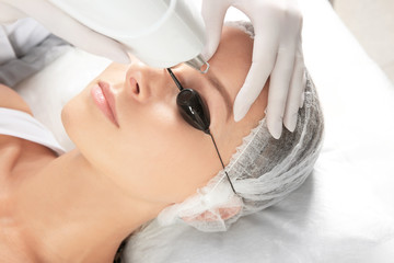 Young woman undergoing laser removal of permanent makeup in salon. Eyebrow correction
