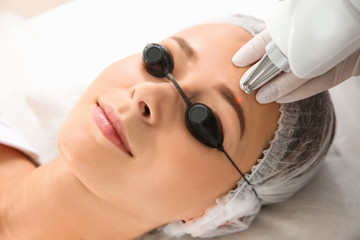 Young woman undergoing laser removal of permanent makeup in salon. Eyebrow correction