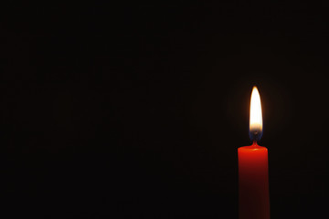 Wax candle burning on black background, closeup