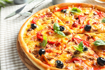 Delicious pizza with olives and sausages on table