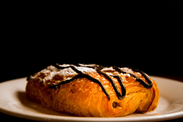 the focus on bread and chocolate on a white dish with black on background