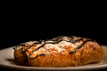 focus of bread and chocolate on white dish with black on background