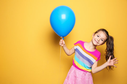 Cute girl with balloon on color background. Birthday celebration