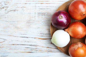 Plate with fresh onions on wooden background, top view