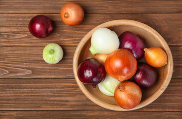 Flat lay composition with fresh onions on wooden background