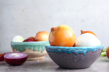Bowl with fresh ripe onions on table