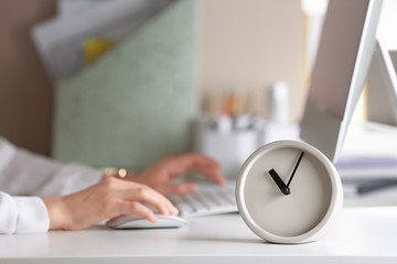 Alarm clock and blurred woman working on background. Time management