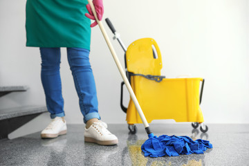 Young woman with mop cleaning stairs