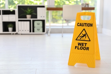 Safety sign with phrase "CAUTION WET FLOOR", indoors