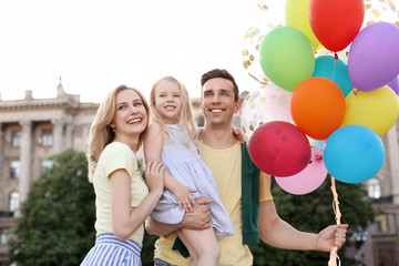 Fototapeta na wymiar Happy family with colorful balloons outdoors on sunny day
