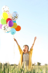 Young woman with colorful balloons outdoors on sunny day