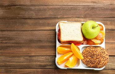 Lunch box with appetizing food on wooden table