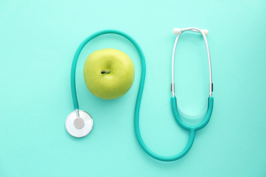 Flat lay composition with stethoscope and apple on color background