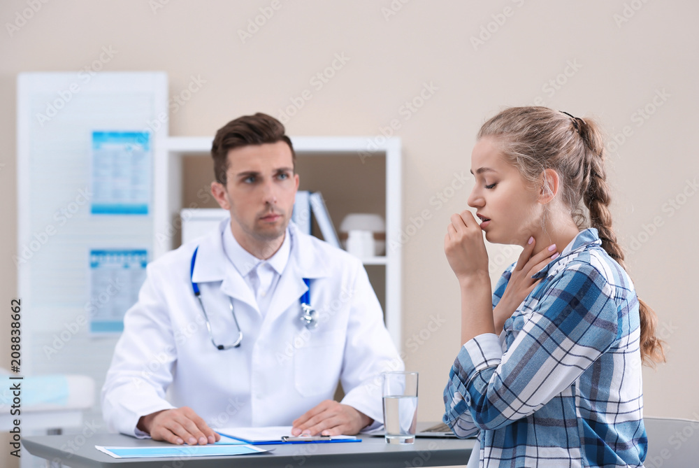 Wall mural coughing young woman visiting doctor at clinic