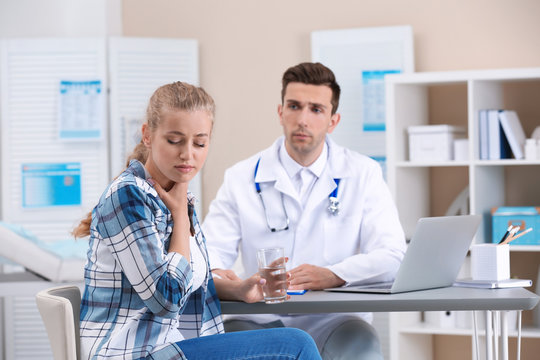 Coughing young woman visiting doctor at clinic