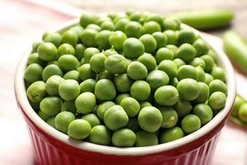 Bowl with green peas on table, closeup