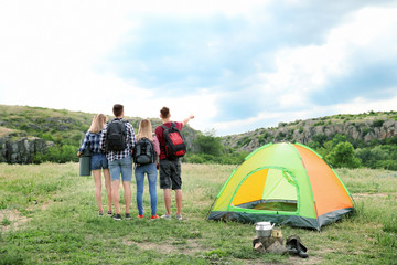 Fototapeta na wymiar Group of young people with backpacks near camping tent in wilderness