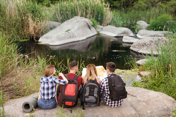 Young people exploring map in wilderness. Camping season