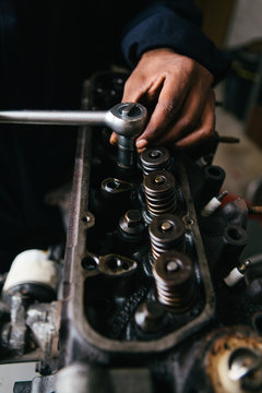 Mechanic fixing an engine for a head gasket repair in a garage.