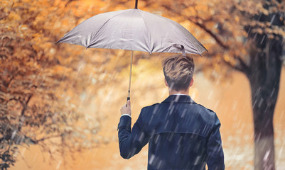 Autumn rainy weather and a young man with an umbrella