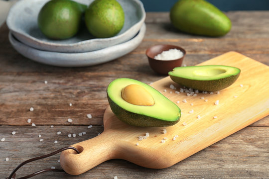 Wooden board with cut avocado on table