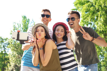 Group of young people taking selfie with monopod outdoors
